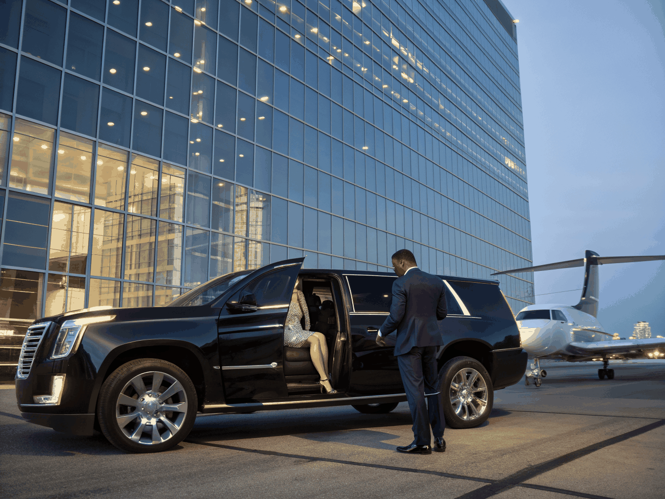 Executive passenger entering rear seat of black luxury SUV outside corporate headquarters